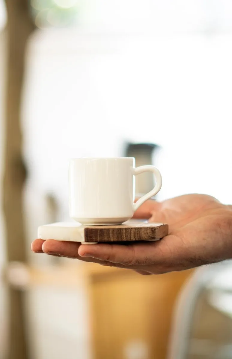 Un café servido en cerámica Atrio, sostenido en la mano